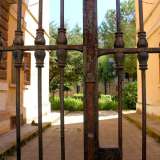 Sul lato opposto invece, quasi a voler dare una boccata d'aria alla rigida monotonia del poligono, interviene una cancellata in ferro, in gran parte sporca di ruggine, oltre la quale si intravede un fitto giardino che avvolge completamente i cortili interni dell'abitato